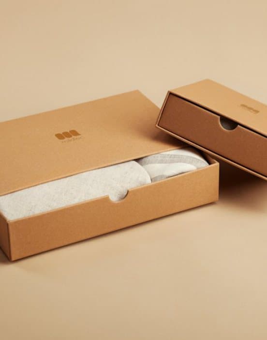 Two plain kraft boxes with folded garments inside
